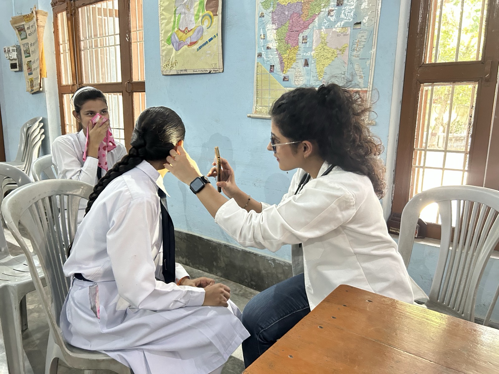 Doctor conducting ear examination of a school student in a classroom