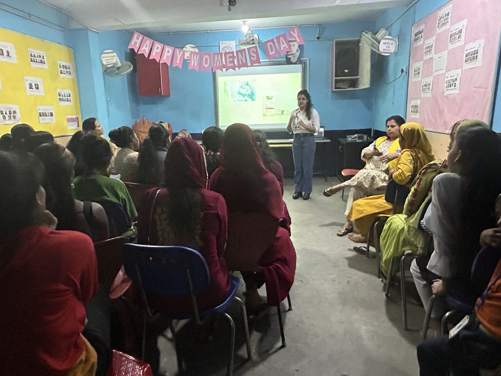 Dr. Sonal leading a Women's Day health education session with a full room of women